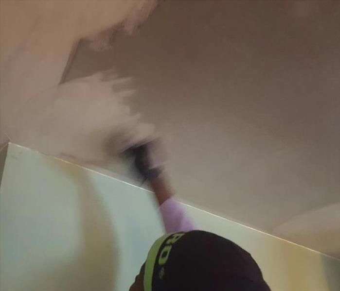 SERVPRO Technician cleaning smoke damage on a ceiling.