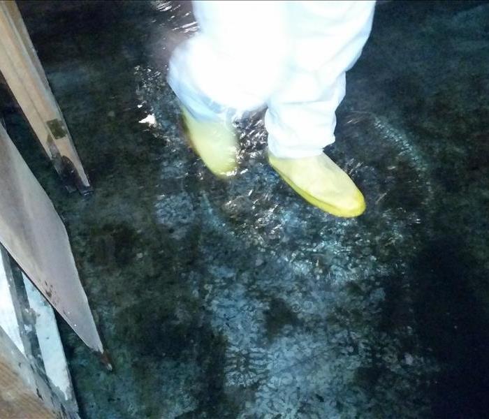 SERVPRO Tech with PPE gear on walking in flooded water in basement.